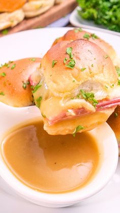 a close up of a sandwich on a plate with gravy and bread in the background