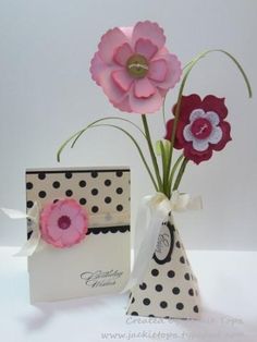 two vases with flowers in them sitting next to each other on a white table