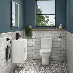 a white toilet sitting next to a sink in a bathroom under a window with blue walls