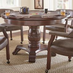 a round table with chairs around it in front of a window and pictures on the wall