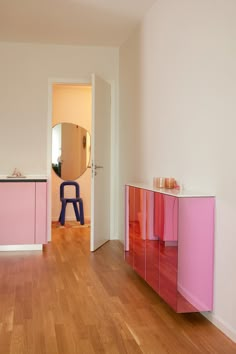 an empty room with wooden floors and pink cabinets