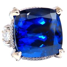 Royal Raised Three stone Tanzanite Ring. GIA Certified: 27.35ct. Natural tanzanite Cushion cut Excellent vivid Violetish Blue Color Measures: 17.02 X 16.94 X 11.59mm VVs- clarity Full cut and brilliant sparkles GIA Report #6224079055 will accompany. Natural Diamonds: .76ct. Rounds, Full cuts G-color, Vs-2 clarity 17.7 grams 18kt. white gold Deck of ring: 19.2 x 19.3mm depth of ring: 11.8mm current ring size: 6 & can be resized, please inquire. $48,000 appraisal certificate will accompany. Luxury Tanzanite Sapphire Ring, Tanzanite Diamond Ring, Handmade Engagement Rings, Three Stone Engagement Ring, Tanzanite Diamond, Tanzanite Ring, Blue Tanzanite, Tanzanite Gemstone, Diamonds Ring