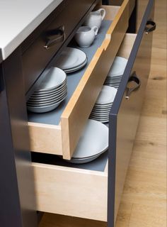 an open drawer with plates and bowls in it