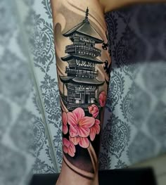 a woman's arm with flowers and pagoda tattoo on it