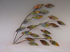 a metal wall sculpture with leaves on it