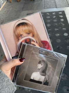 a woman holding up a cd in front of her face with the cover pulled back