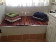 two towels are sitting on a wooden bench in the bathroom, next to a window