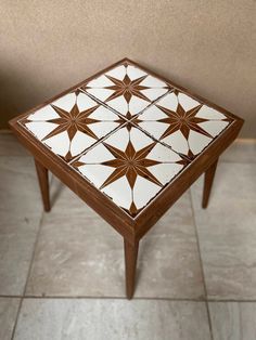 a wooden table with white and brown tiles on it's top, sitting on tile flooring