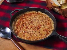 a pan filled with food sitting on top of a wooden table next to a knife and fork