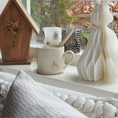 a window sill with coffee mugs and other items on it next to a birdhouse