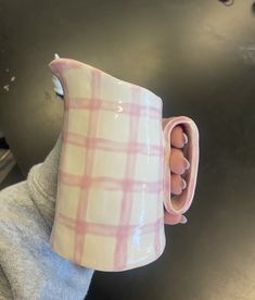 a person holding a pink and white coffee mug