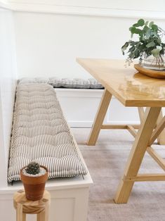 a wooden bench sitting next to a table with a potted plant on it