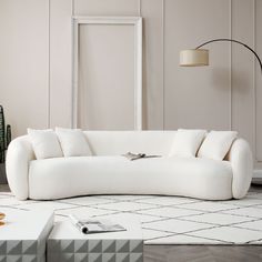 a white couch sitting on top of a rug in a living room next to a lamp