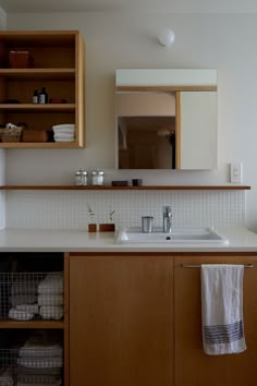 a bathroom sink sitting under a mirror next to a shelf filled with towels and other items