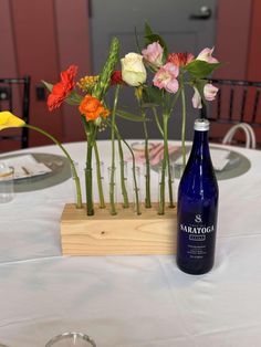 there are many flowers in the vases on the table with wine bottles next to them