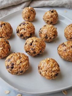 a white plate topped with lots of oatmeal covered balls on top of a table