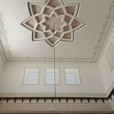 an ornate ceiling in the middle of a room with white walls and decorative designs on it