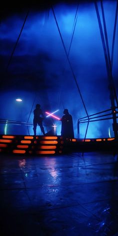 two people standing on a stage with lights in the background