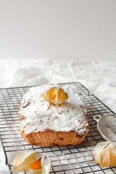 a pastry on a cooling rack with powdered sugar and fruit toppings next to it