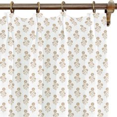 a white curtain with brown flowered design on the top and bottom, hanging from a wooden rod