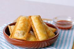 some food is in a bowl on a blue and white towel next to dipping sauce