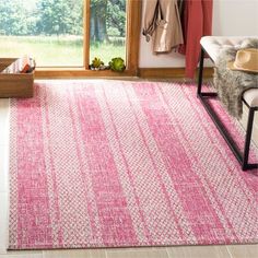 a living room with a pink rug on the floor next to a chair and window