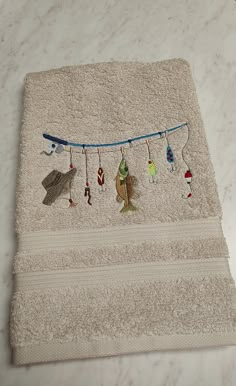 towels with embroidered fish hanging from them on a white countertop in front of a marble wall