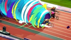 three women in wheelchairs race around a colorful tunnel on a track with spectators watching from the sidelines