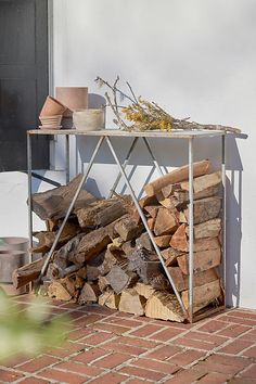 a pile of firewood sitting on top of a brick floor next to a building