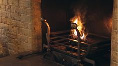 a fire burning inside of a brick fireplace next to a black iron frame and door