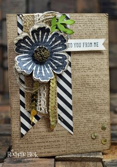 a close up of a card with a flower and ribbon attached to it on a wooden table