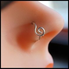 a close up view of a person's nose with a small earring in the shape of a treble