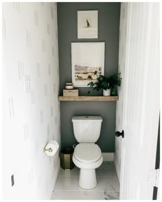 a white toilet sitting in a bathroom next to a wall mounted art above the toilet