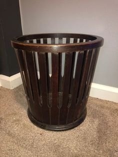 a wooden trash can sitting on the floor next to a wall and carpeted floor