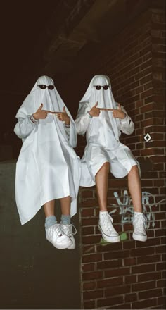 two people dressed in white sitting on a brick wall