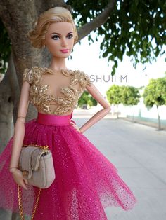 a barbie doll wearing a pink dress and holding a handbag in front of a tree