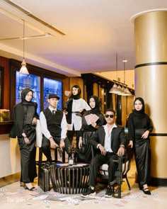 a group of people standing around each other in front of a table and two chairs