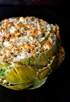 an artichoke dish is shown on a black plate with parmesan cheese