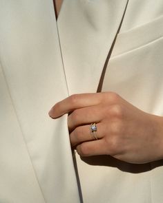 a woman's hand with a ring on her left wrist, wearing a white coat