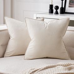 two white pillows sitting on top of a couch