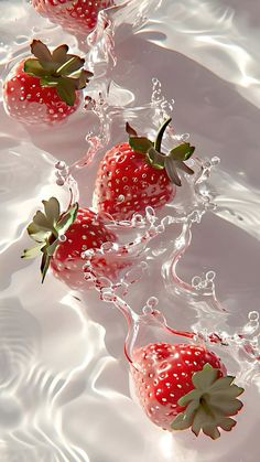 three strawberries are floating in the water and splashing on top of each other