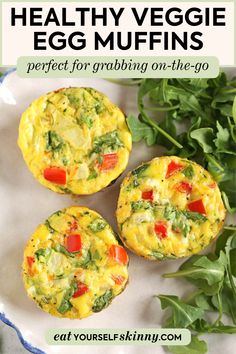 three egg muffins on a plate with spinach and carrots in the background