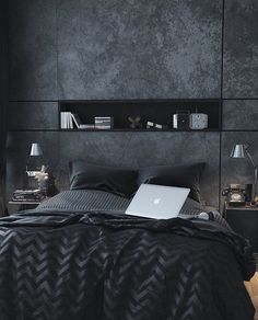 a laptop computer sitting on top of a bed next to a night stand and lamp