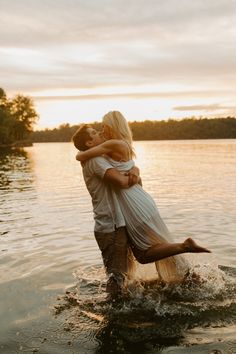 a man and woman are hugging in the water at sunset, while they both have their arms around each other