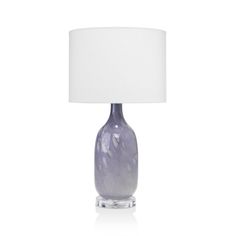 a glass table lamp with a white shade