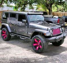 a gray jeep with pink rims parked in a parking lot