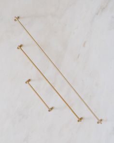 three gold pins on a white marble surface