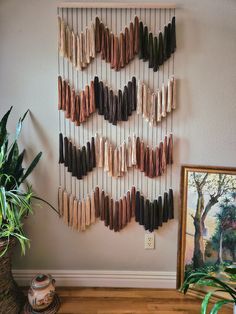 a wall hanging made out of wood sticks and some plants on a table next to a potted plant