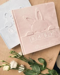 two personalized baby blankets with bunny ears on them next to white flowers and greenery