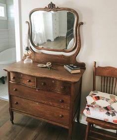 an old dresser with a mirror on top and a wooden chair in the foreground